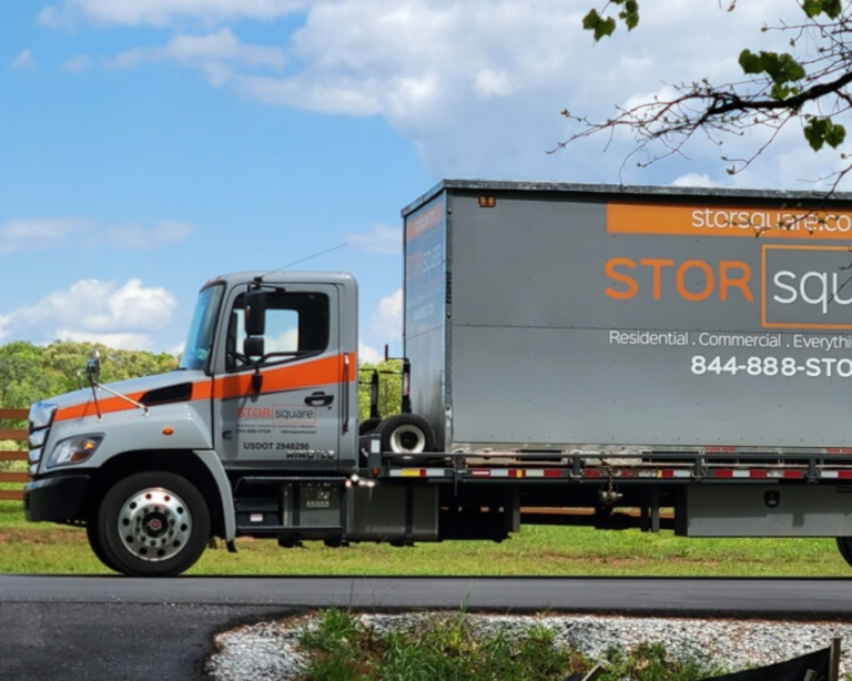 STORsquare delivery truck transporting a portable storage container along a residential road in Woodstock Georgia