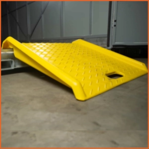 Yellow loading ramp positioned at a moving container entrance, designed for dollies and pallet jacks during loading and unloading.