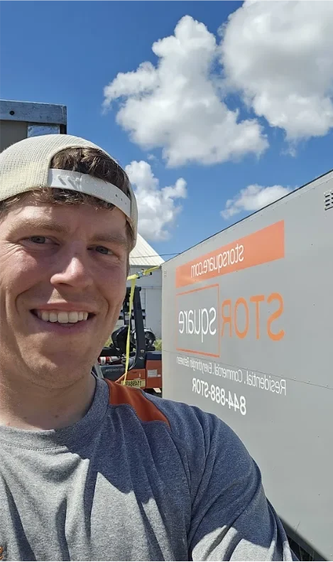 A STORsquare team member standing beside a mobile storage unit during an outdoor container delivery on a clear day.