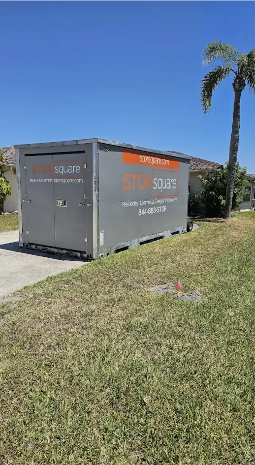 STORsquare portable storage container placed on a residential lawn beside a driveway, set up for on-site storage at a Florida home.