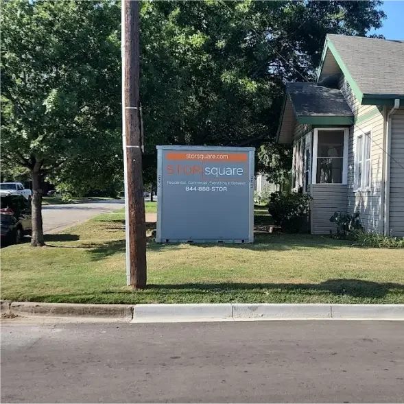 A STORsquare portable storage container placed on a residential lawn beside a single-story home along a neighborhood street.