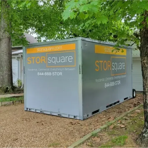 STORsquare portable storage container placed in a residential yard beside a home, positioned for on-site storage in Tennessee.