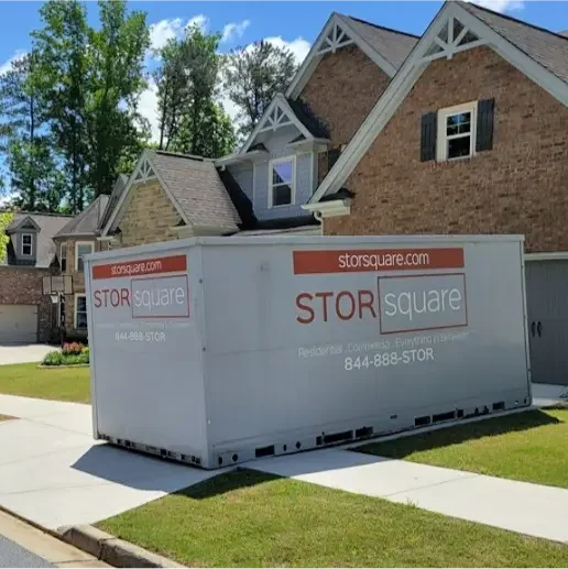 Two STORsquare portable storage containers placed along a residential driveway in a suburban neighborhood, set up for moving or storage in Tennessee.