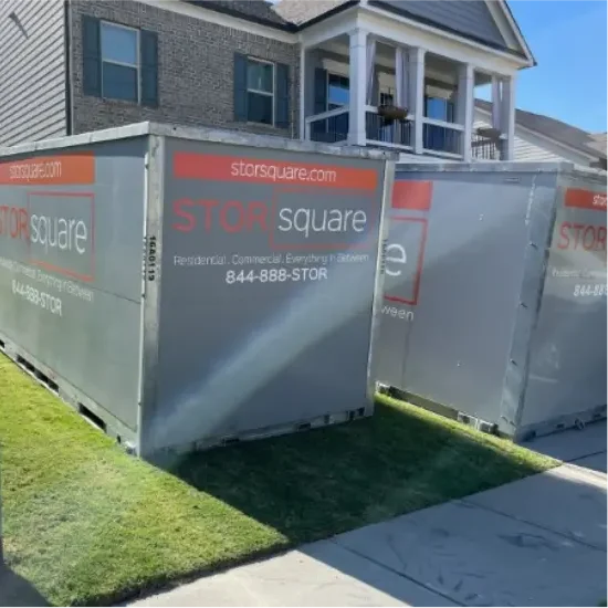 Two STORsquare portable storage containers placed on a residential lawn beside a townhome during a local delivery.