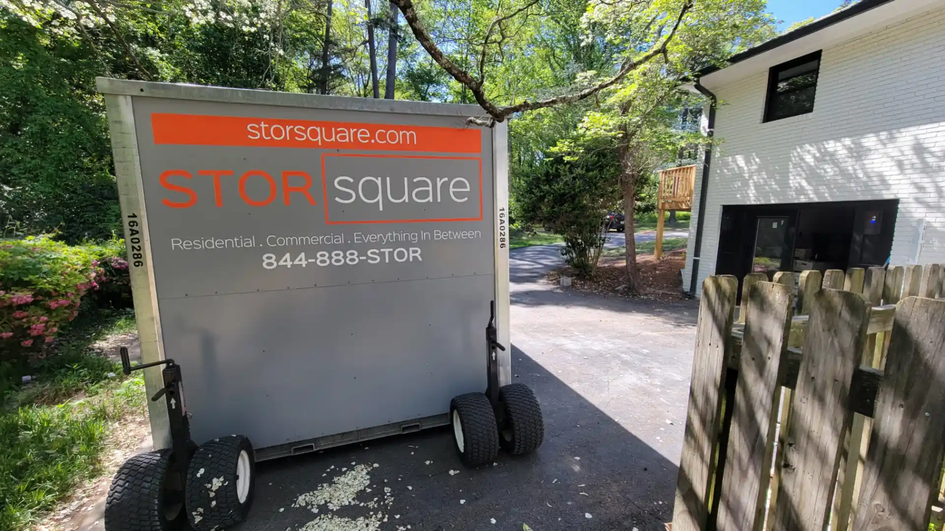 Portable storage container positioned in a driveway for short-term storage during a move.