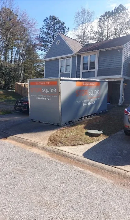 Two STORsquare storage containers set side by side along a shared residential driveway outside a townhouse in North Carolina.