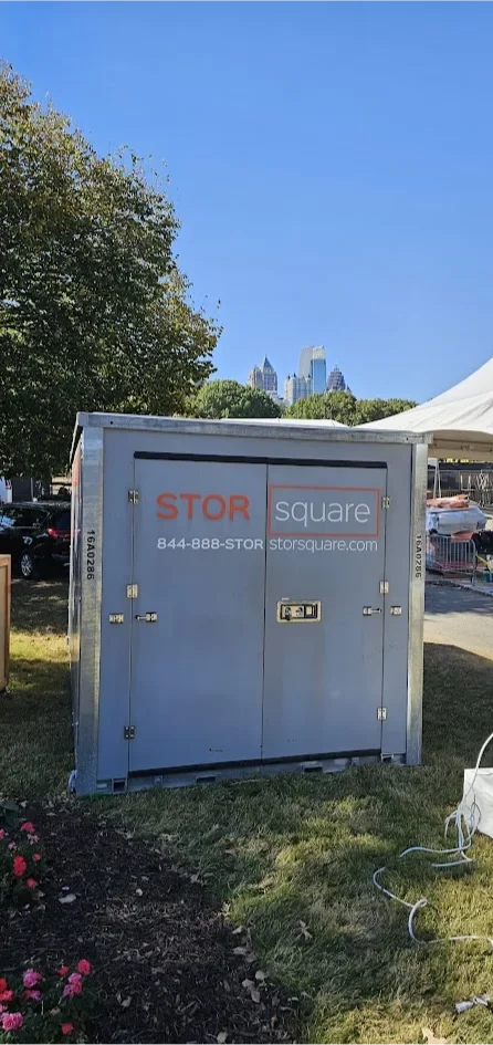 STORsquare portable storage container placed on grass beside tents and event equipment, used for temporary storage at an outdoor site in North Carolina.