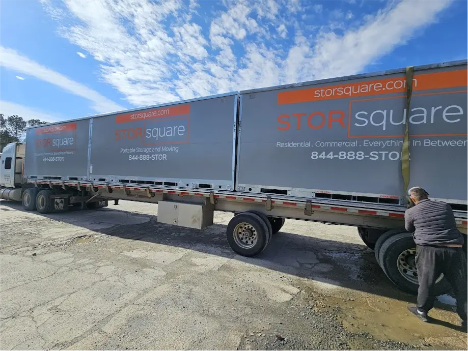 Multiple STORsquare portable storage containers secured on a flatbed truck during transport in Charlotte, NC.