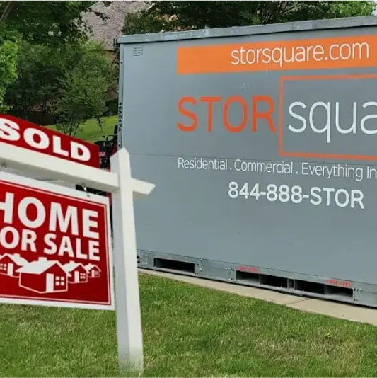 STORsquare storage container positioned beside a sold home sign on a residential lawn during a move-out transition in North Carolina.