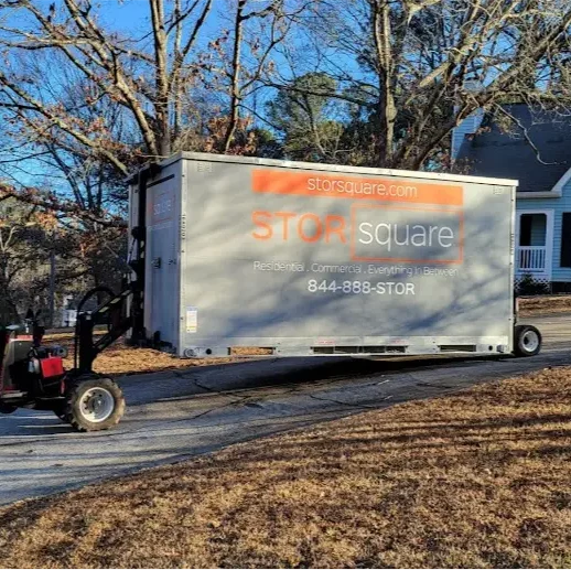 STORsquare storage container being positioned on a sloped residential driveway using placement equipment in a North Carolina neighborhood.