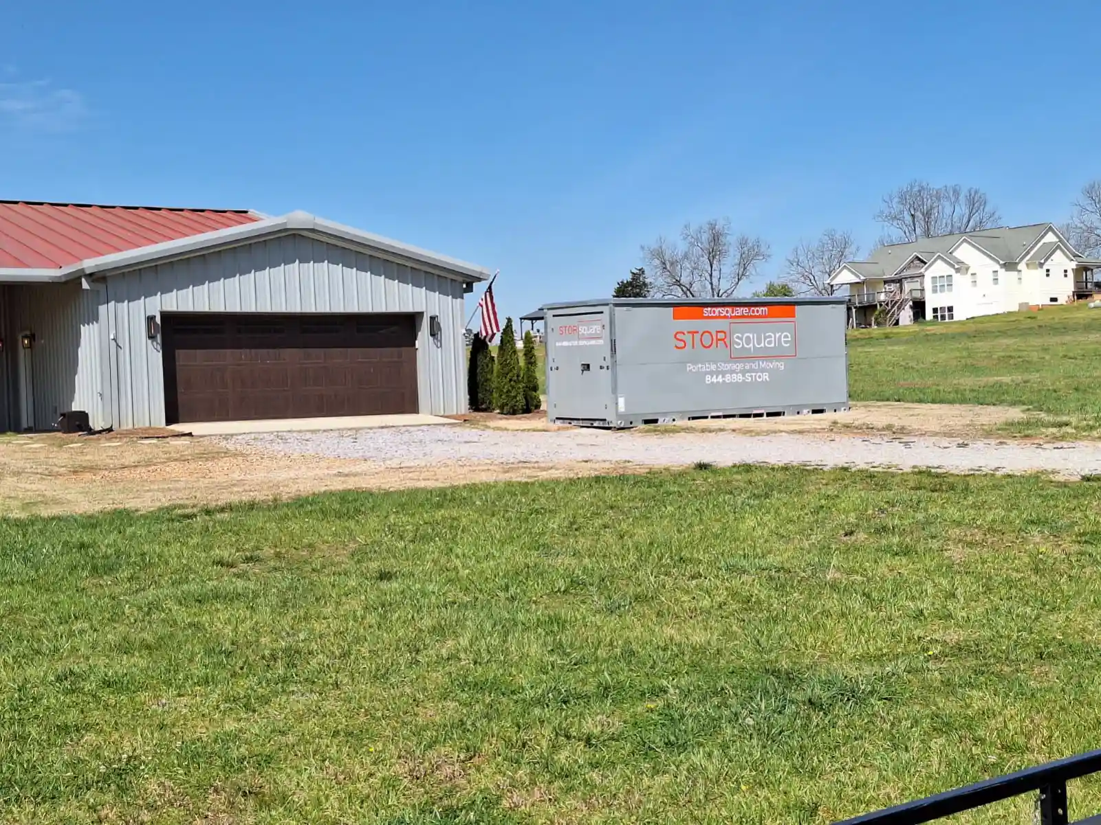 Portable storage container beside a home driveway during a move
