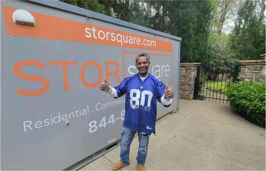 Customer giving a thumbs-up beside a STORsquare portable storage container at a residential property in Kissimmee, FL.