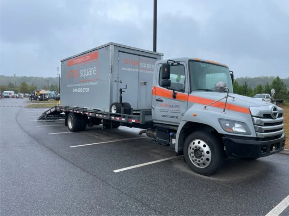 STORsquare mobile storage container on a delivery truck in a Gainesville GA parking lot during rainy conditions.