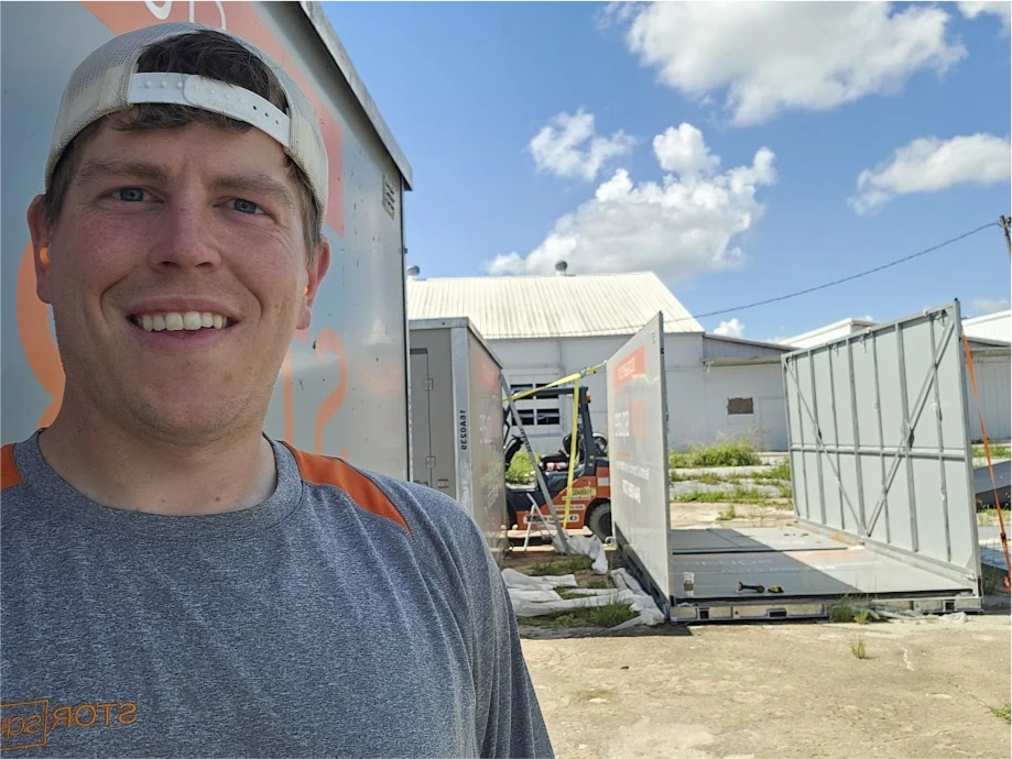 STORsquare team member standing near portable storage containers being set up in a Plant City FL yard with equipment visible.