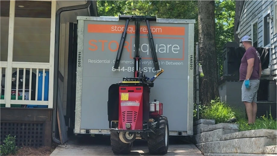 STORsquare portable storage container being placed in a tight Winter Haven FL driveway using delivery equipment beside a home.