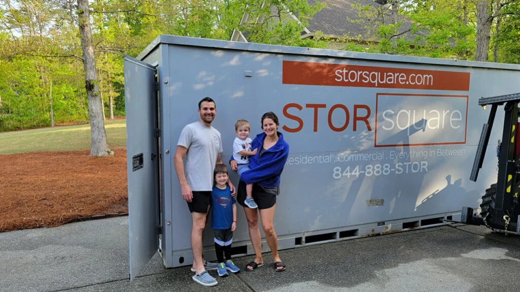 Family standing beside a STORsquare container for portable storage units moving during a long-distance relocation