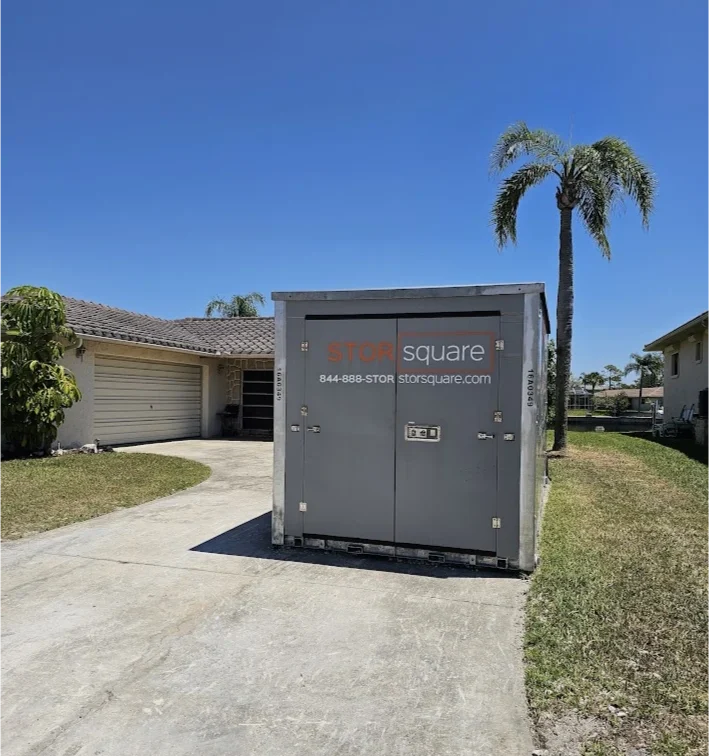 STORsquare long-distance moving container placed on a residential driveway in Florida beside a home and palm tree