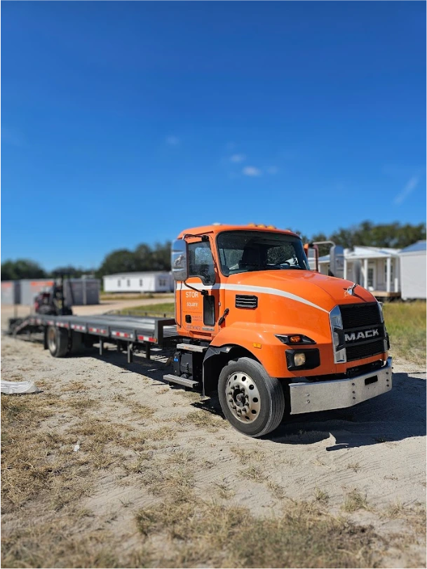 STORsquare mobile storage units delivery truck parked on a work site in Canton, GA with flatbed trailer ready for transport