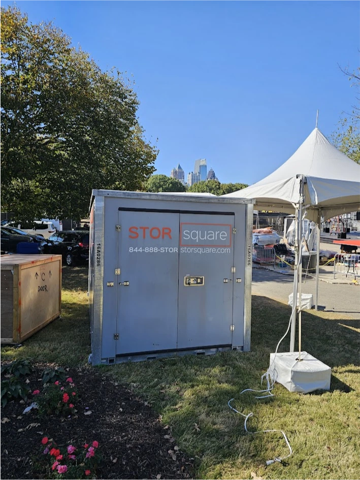 STORsquare long-distance moving container placed at an outdoor event site in Orlando near tents, parked cars, and skyline views