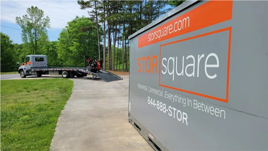STORsquare portable moving and storage container in Orlando beside a delivery truck and ramp on a residential driveway