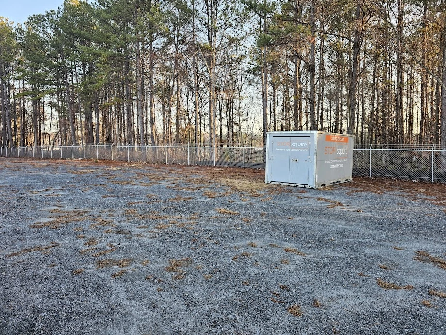STORsquare portable storage units placed in a Buford fenced yard with open space and tree line in the background