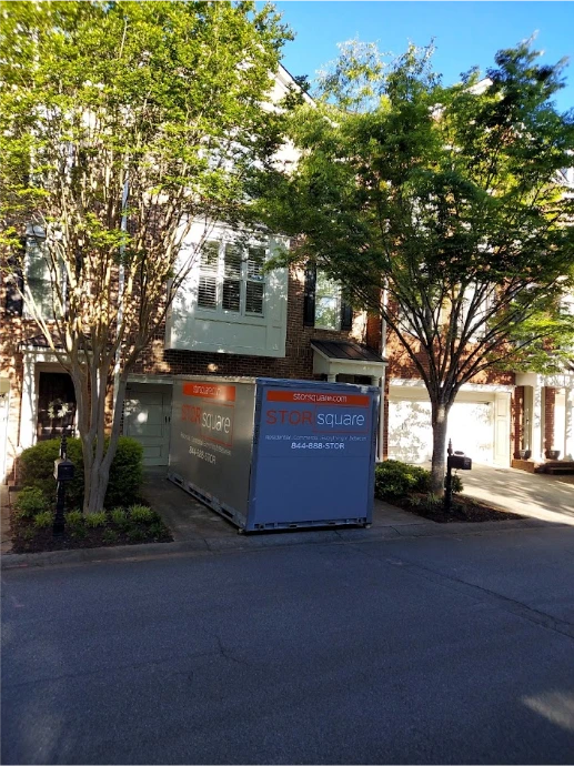 STORsquare portable moving and storage container placed in front of a townhome driveway in Tampa between residential buildings and trees
