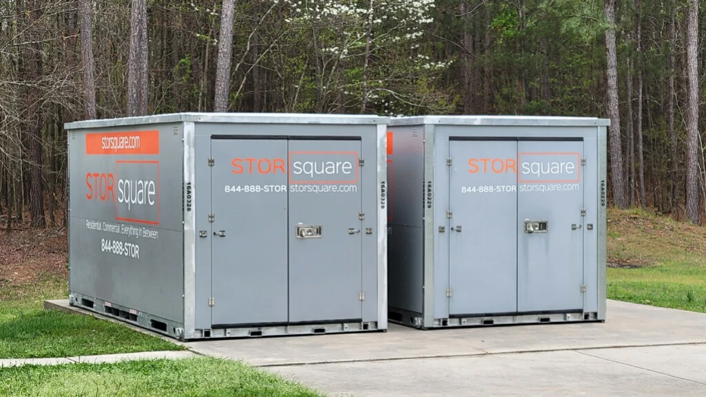 Two portable storage containers used as temporary storage solutions during a larger garage floor coating or remodeling project