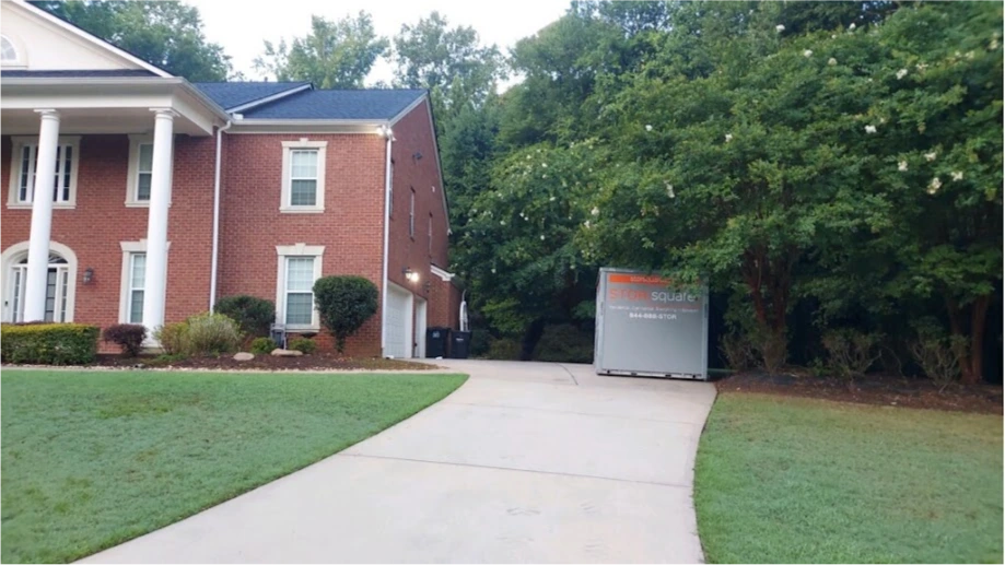 STORsquare portable storage container at the end of a Bellaire residential driveway beside a brick home.