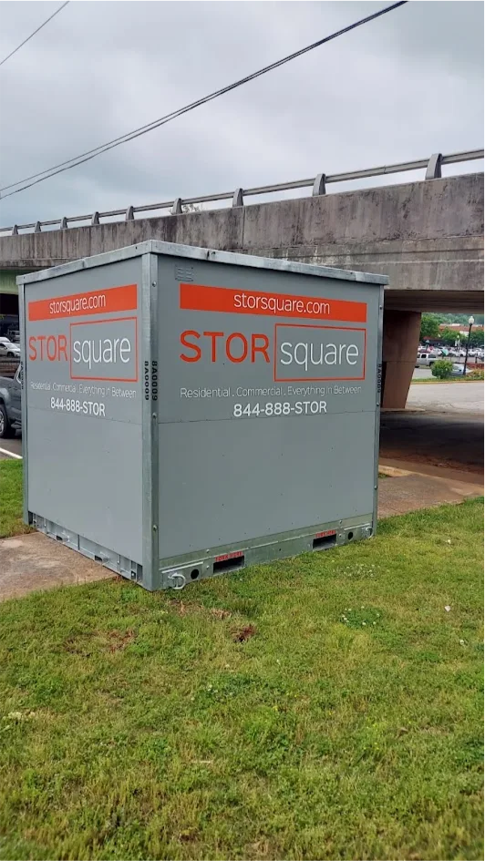 STORsquare portable storage container placed on grass in Norcross, GA beside an overpass near a roadside area.