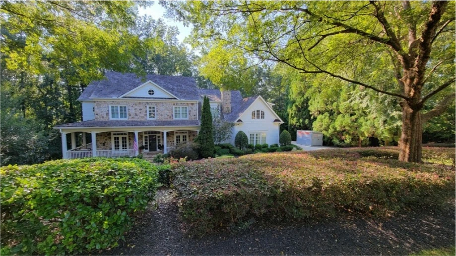 STORsquare storage container placed near a Fulshear home with a wooded driveway and landscaped front yard.