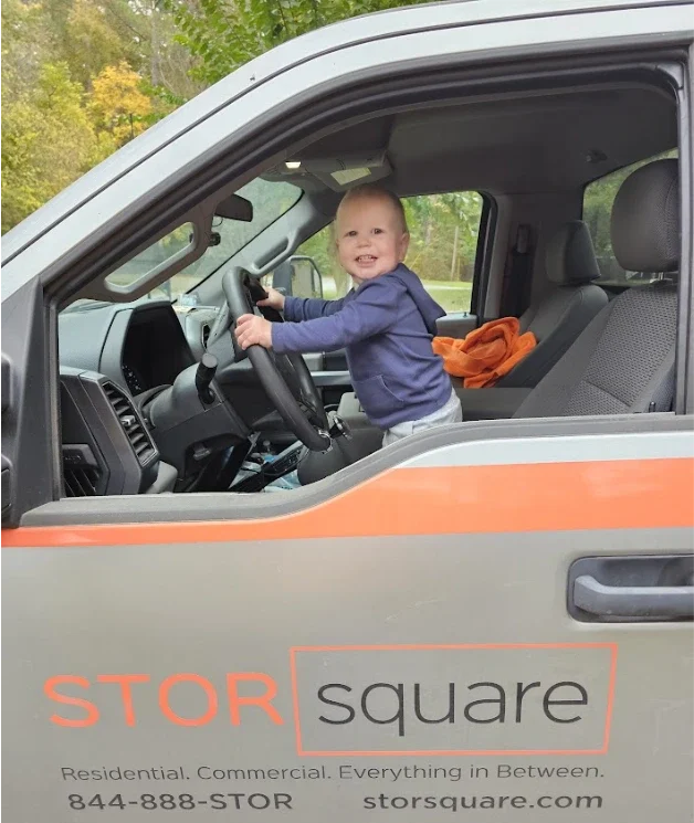 Smiling child sitting in the driver’s seat of a STORsquare truck cab in Manvel.