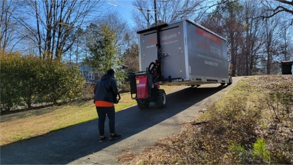 STORsquare Mule equipment placing a storage container on a sloped Pearland driveway with a team member nearby.