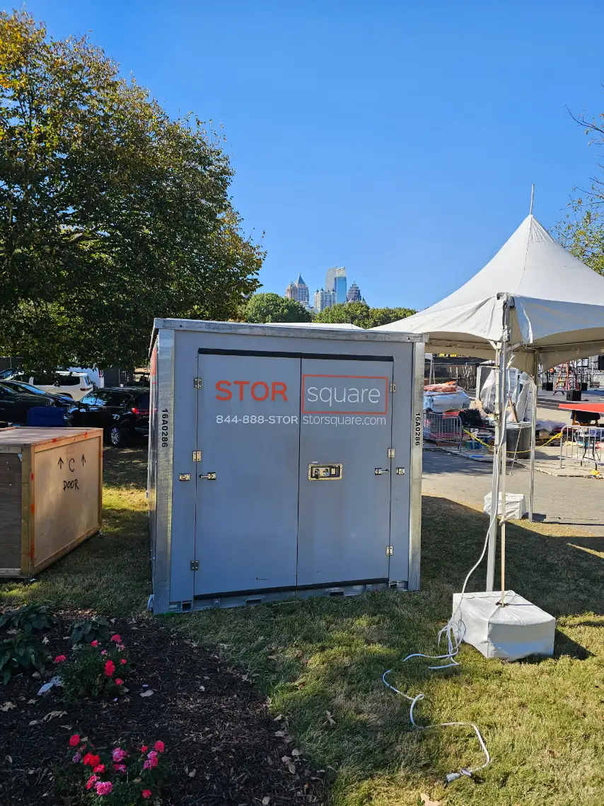 A STORsquare portable storage container placed beside an outdoor tent, creating a clean and visible setup for sorting, staging, or event storage.