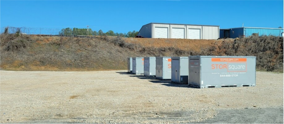 STORsquare storage containers lined up in a Richmond gravel yard near industrial buildings.