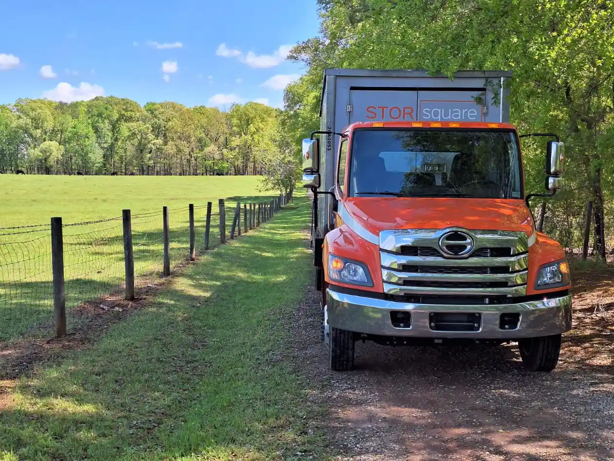 STORsquare truck delivering a job site storage container to a rural work area.