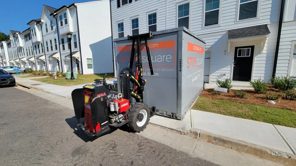 Mobile storage container being positioned in front of a townhome for loading.