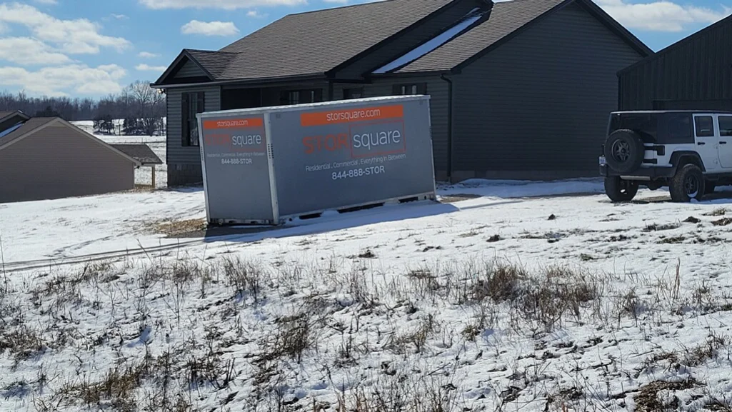 Portable storage container positioned beside a home during a winter move.