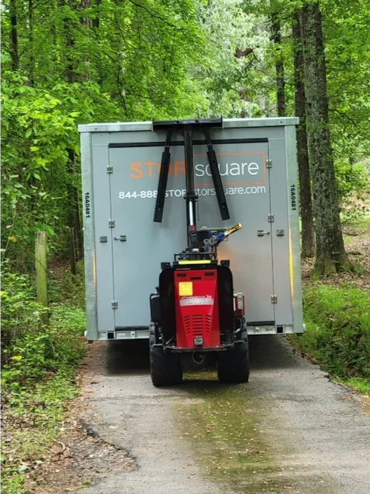 STORsquare mobile storage container in Calhoun being positioned on a narrow wooded driveway.