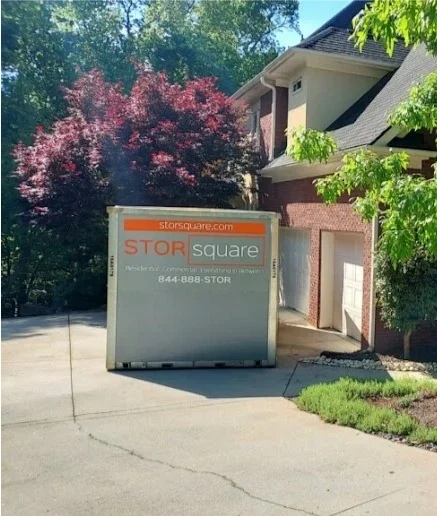 STORsquare mobile storage container in Sweetwater placed in the driveway of a brick home under trees.