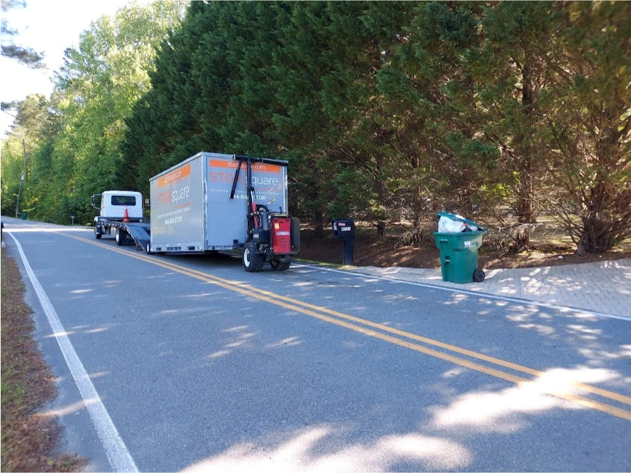 STORsquare moving container being delivered along a tree-lined road in Resaca.