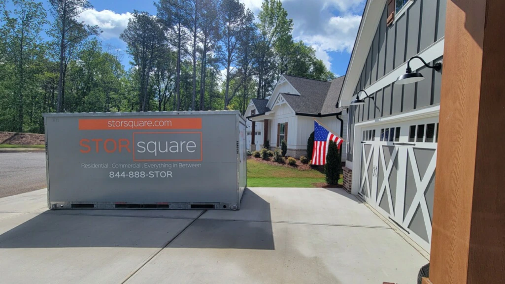 STORsquare moving container placed beside a residential garage for flexible packing and storage