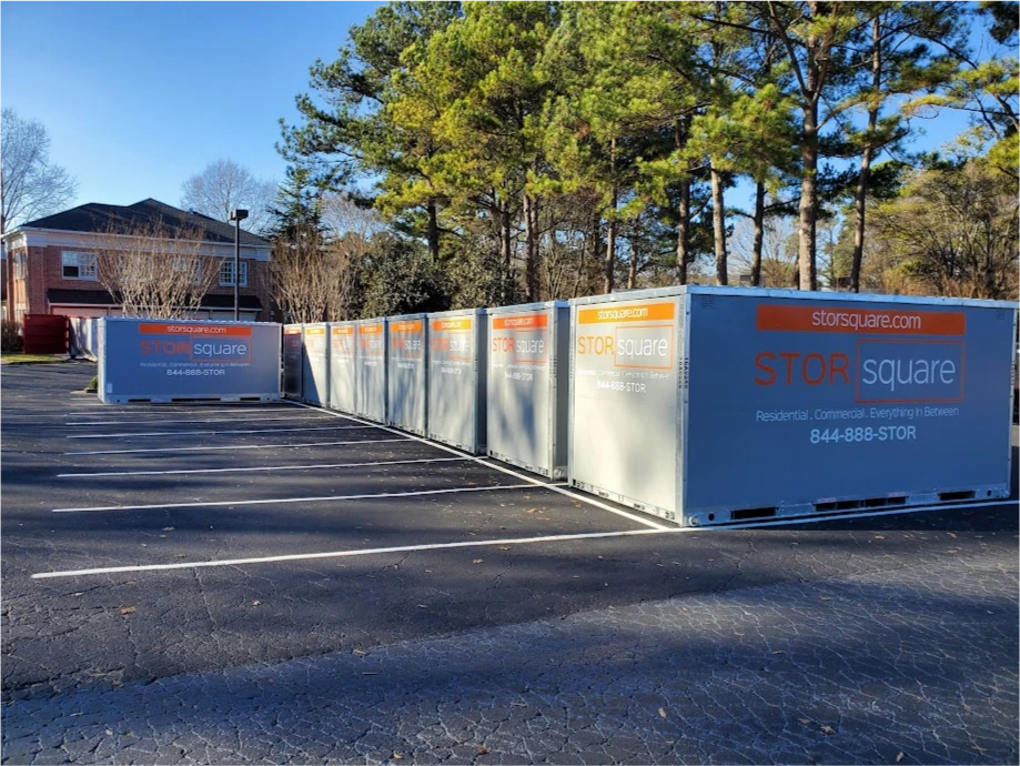 Row of STORsquare portable storage containers placed in a Weddington parking lot near trees.