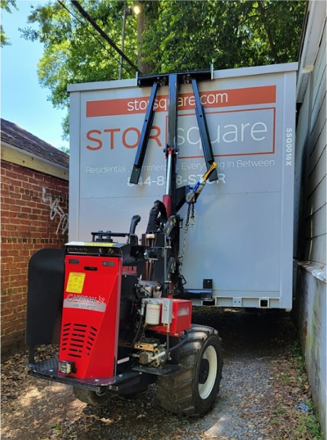 STORsquare moving container positioned by the MULE system in a narrow gravel passage between buildings, demonstrating placement in Morganton, NC.
