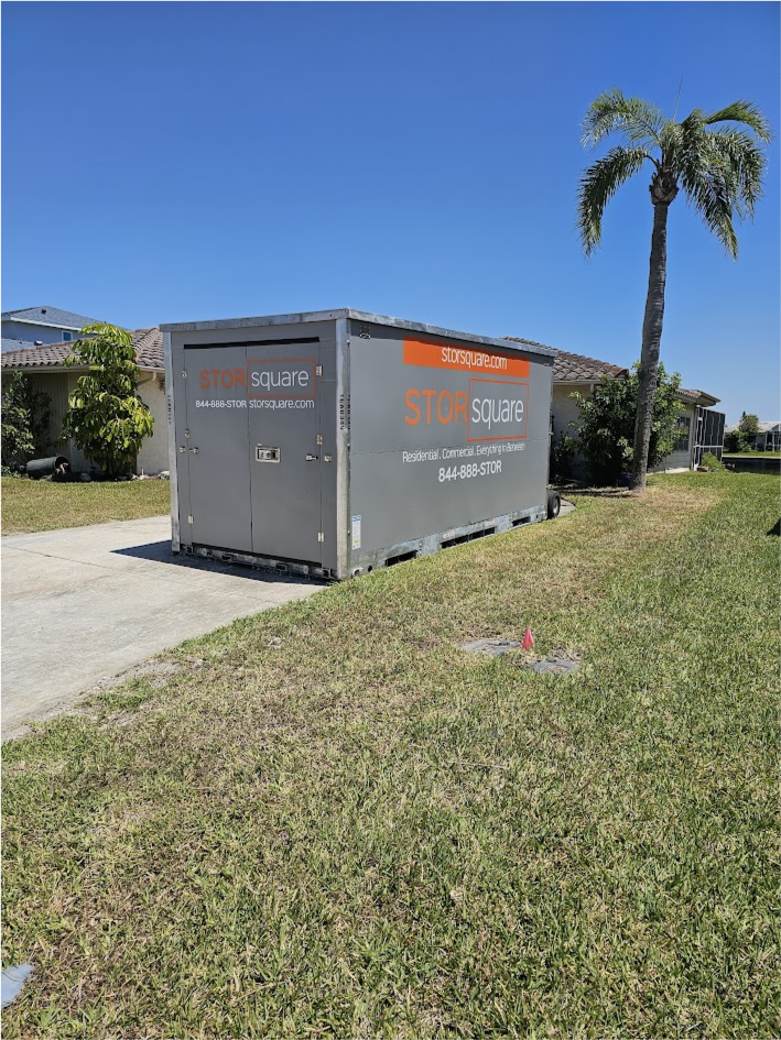 STORsquare portable storage container placed on a residential driveway in Brandon, FL, beside a grassy lawn and tall palm tree, with single-story homes in the background.