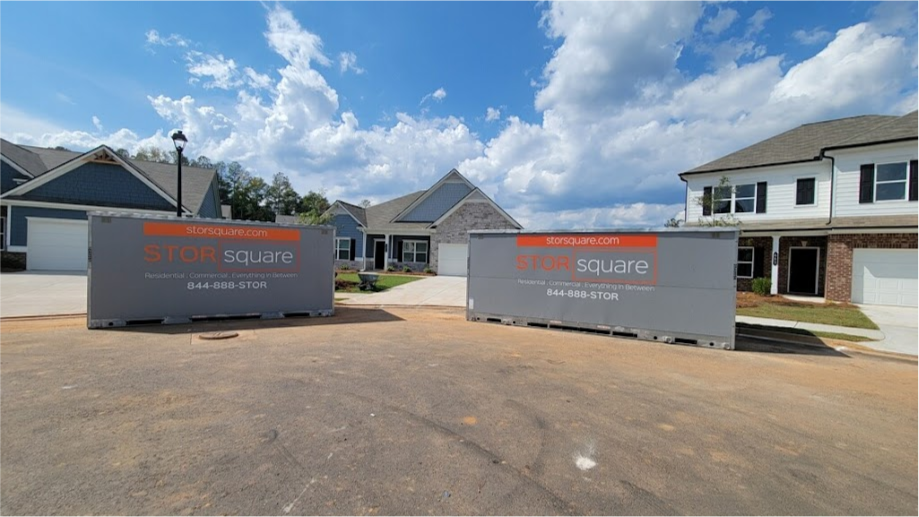 Two STORsquare portable storage containers positioned along a residential street in Brandon, FL, in front of several houses with garages under a partly cloudy sky.